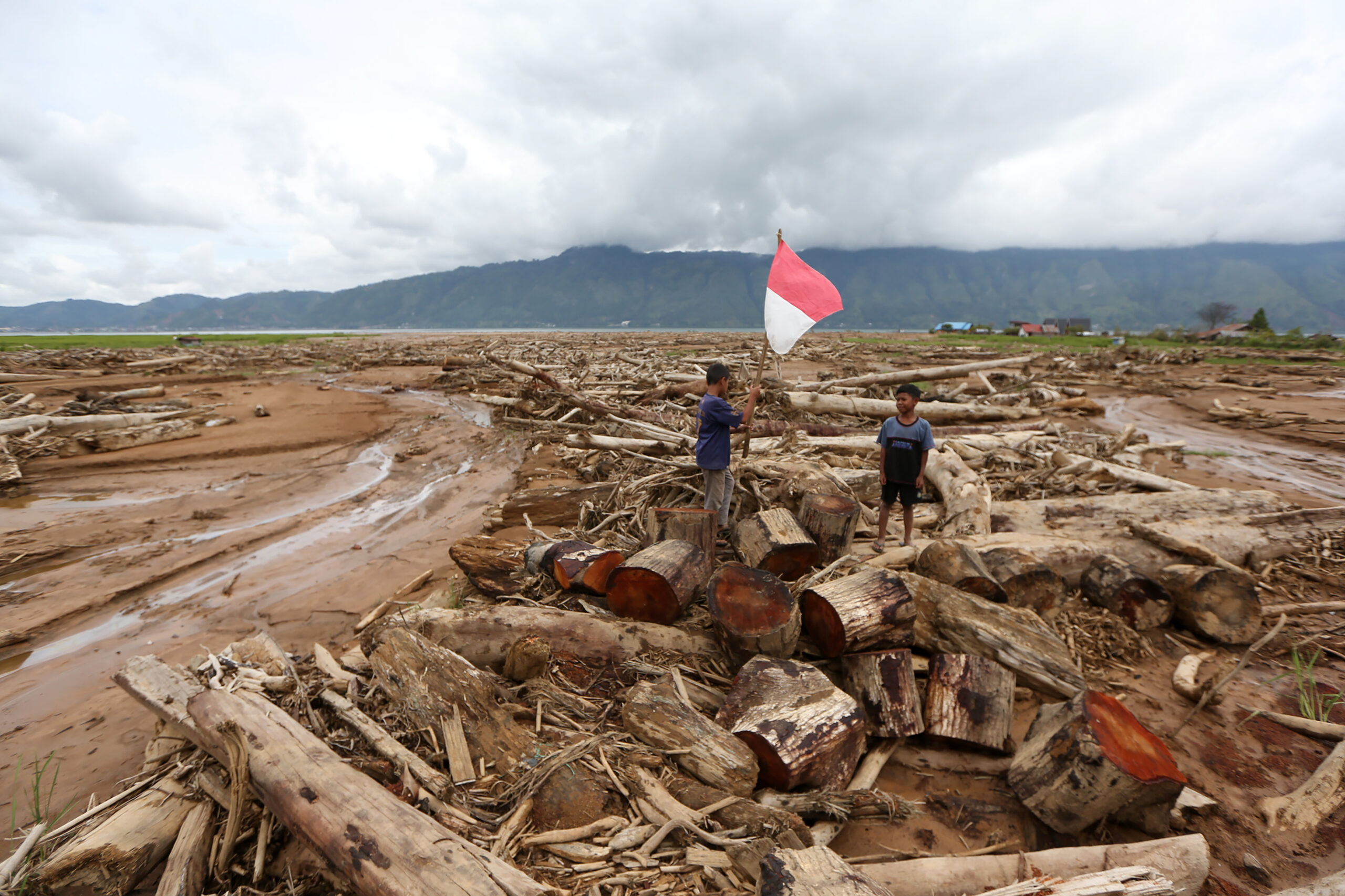 Anak-anak bermain di antara puing kayu yang terbawa arus banjir dan tanah longsor yang menimbun area pertanian di Desa Toweren Uken, Lut Tawar, Aceh Tengah, Aceh, Jumat (2//1/2026). (Foto: Antara/Irwansyah Putra)