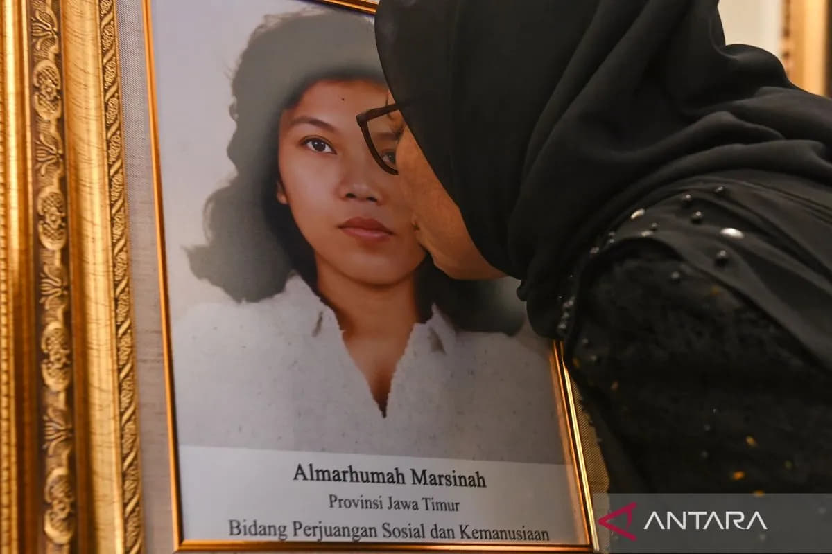Adik aktivis buruh Marsinah, Wijiyati, mencium foto kakaknya usai mengikuti upacara pemberian gelar pahlawan kepada Marsinah dan sembilan tokoh lainnya di Istana Negara, Jakarta, Senin (10/11/2025). (Foto: Antara/Aditya Pradana Putra)