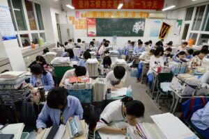 Suasana kelas khusus bimbingan belajar persiapan gaokao. Para siswa terlihat berlatih mengerjakan soal ujian di meja yang dipenuhi tumpukan buku dan diktat pelajaran. (Foto: scmp.com)